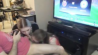 Мужик играет в видео игры и одновременно даёт на рот сразу двум подружкам хуесоскам